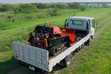 芝生の屋外エリアで建設機械を運ぶユーティリティトラック。