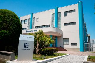 日章旗が掲げられた大きなオフィスビルと庭園の外観。