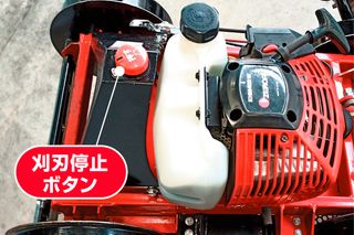 ブレードストップボタンと燃料タンクを示す芝刈り機の上面図。